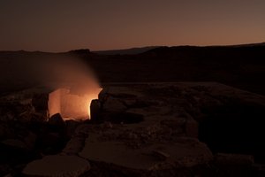 Steinlandschaft in der Nacht, in der Mitte des Bildes bricht der Boden auf und Licht scheint durch.