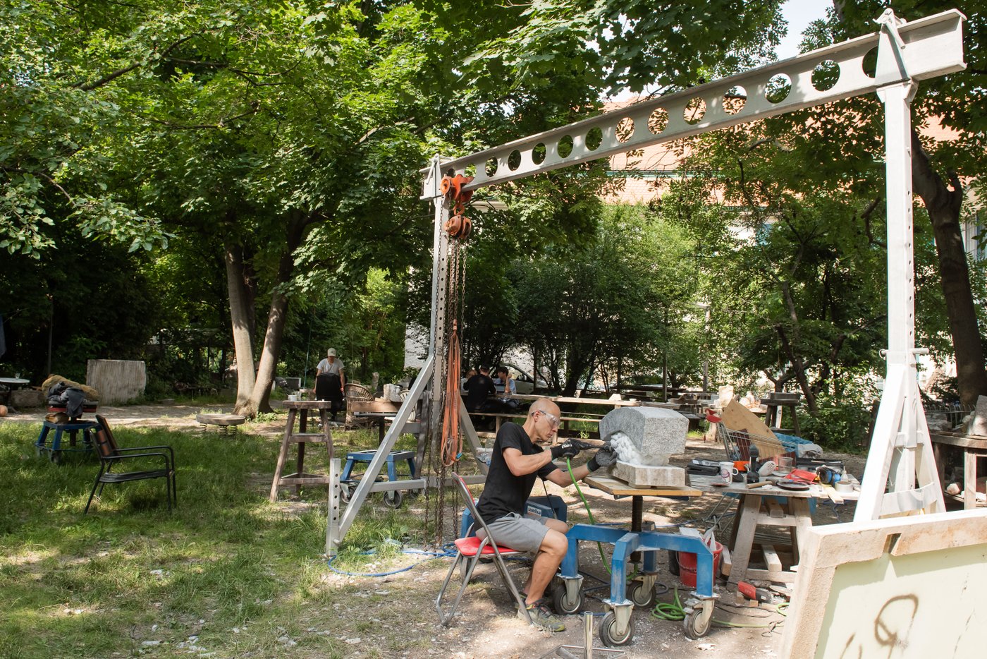 Ein Bildhauer im Garten arbeitet an seinem Objekt