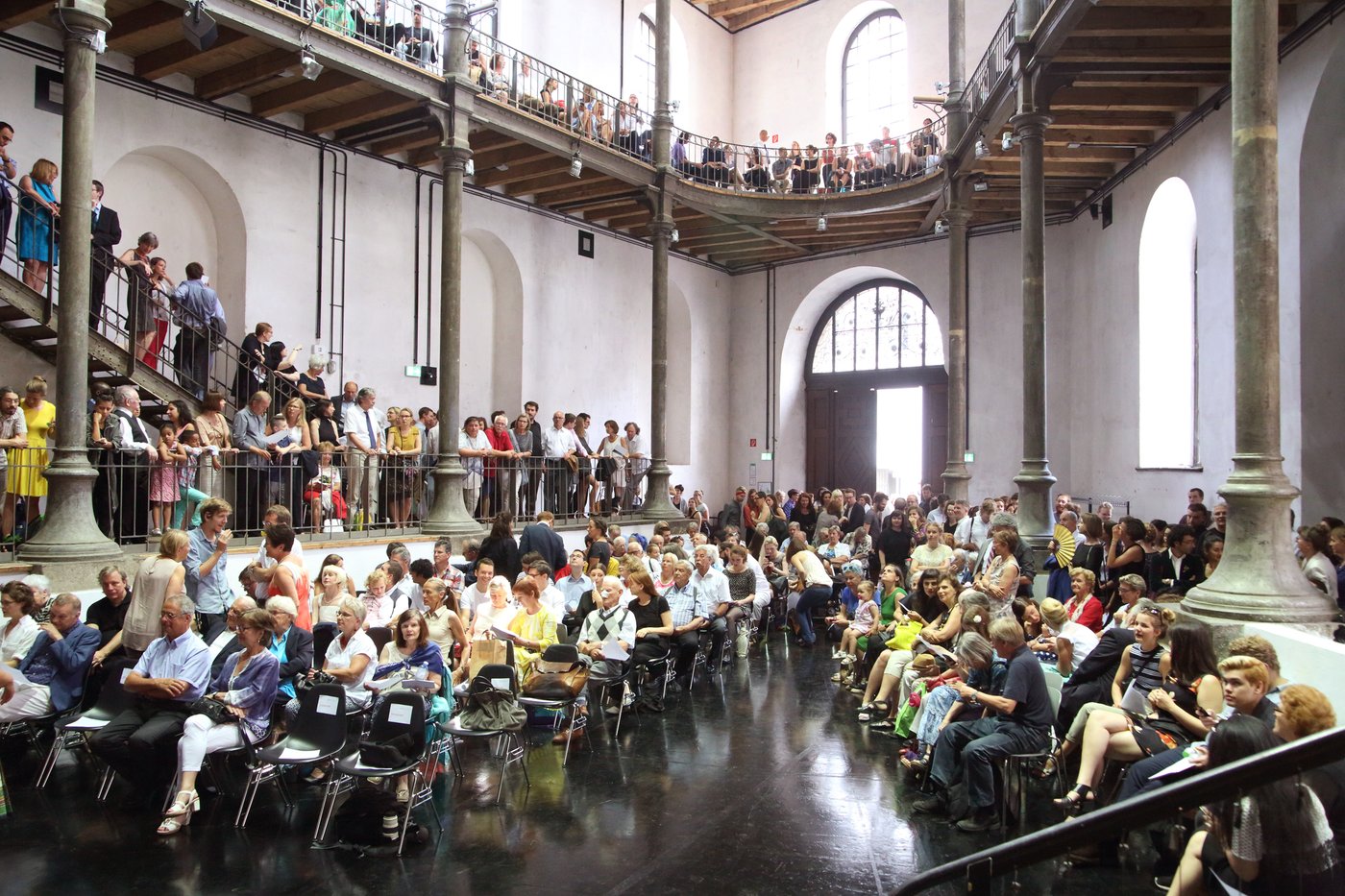 Viele Menschen warten im Prospekthof (großer hoher Raum über 4 Stockwerke mit Galerien auf jedem Stockwerk) auf den Beginn der Abschlussfeier 2016 der Akademie der bildenden Künste Wien.