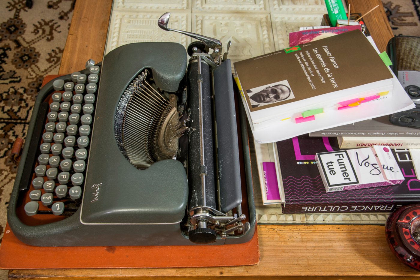 Picture of a desk, with an old typewriter and some books, including Frantz Fanon's “Les Damnés de la Terre”.