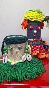 Two dolls can be seen in the picture, scraps of fabric and knitting yarn form colorful garments on the lower part of the bodies. Eyelets and buttons draw abstract faces that are crowned with shells, beads and ribbons.