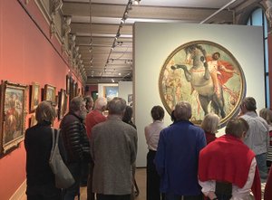 a group of people in an exhibition tour in a room full of oil paintings