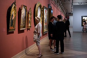 people at an exhibition opening in front of paintings