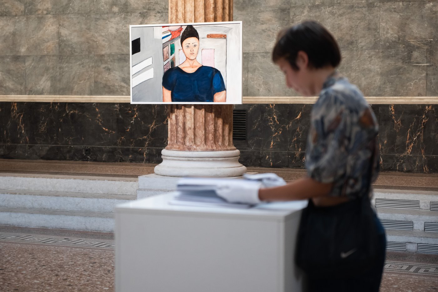 Person standing in front of a book and in the background a picture in focus