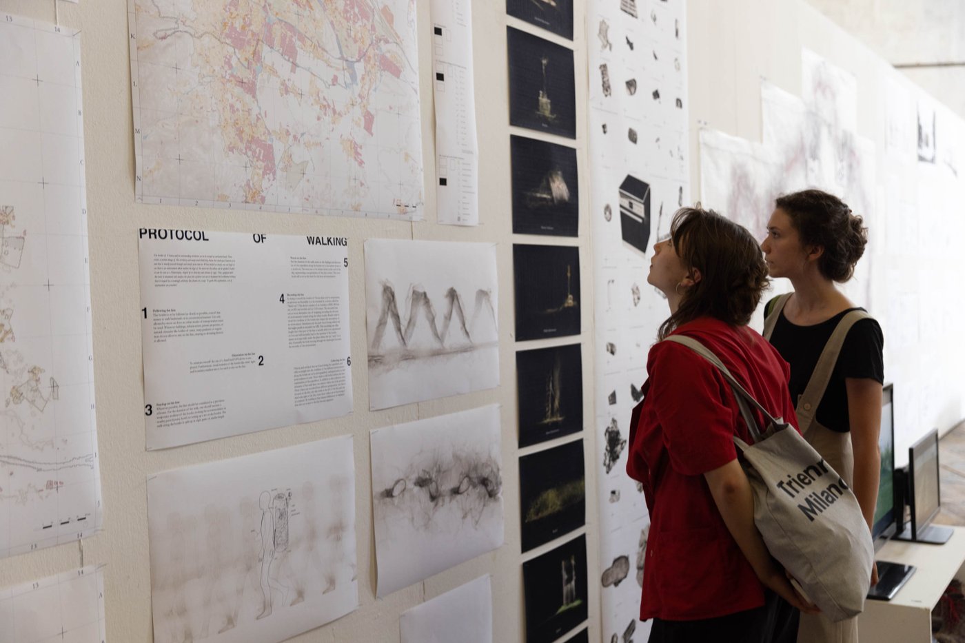 Two people looking at city maps that are nailed to a wall