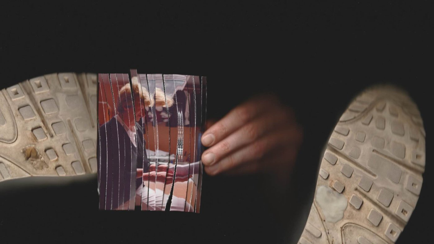 A shredded picture is being taken from underneath a pair of worn-out sneakers.