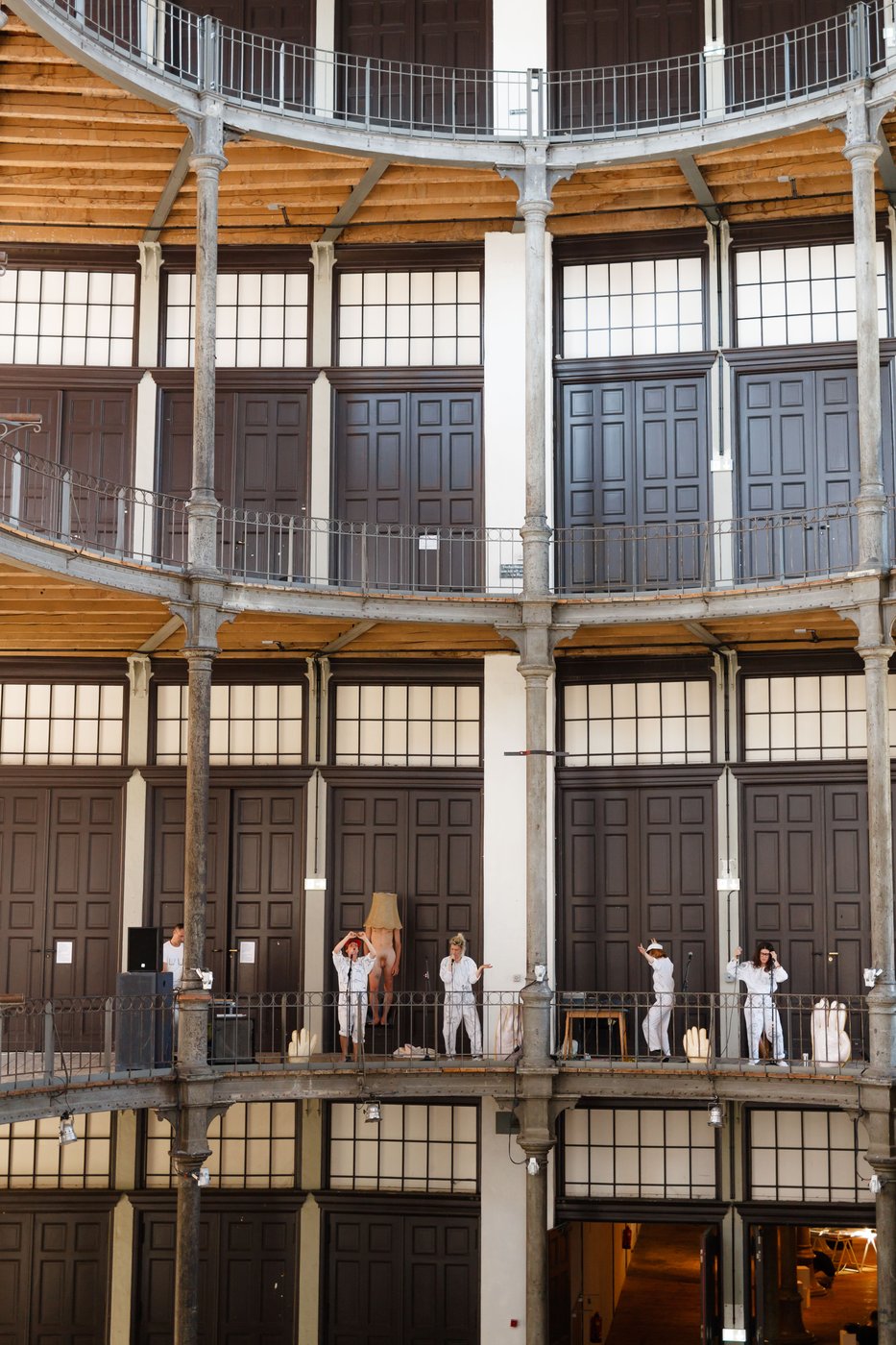 You can see the galleries of the Prospekthof from the front. On the lowest one 5 artists in white overalls perform singing and dancing.