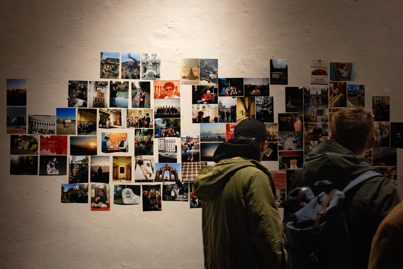 people walking by a wall full of photographs